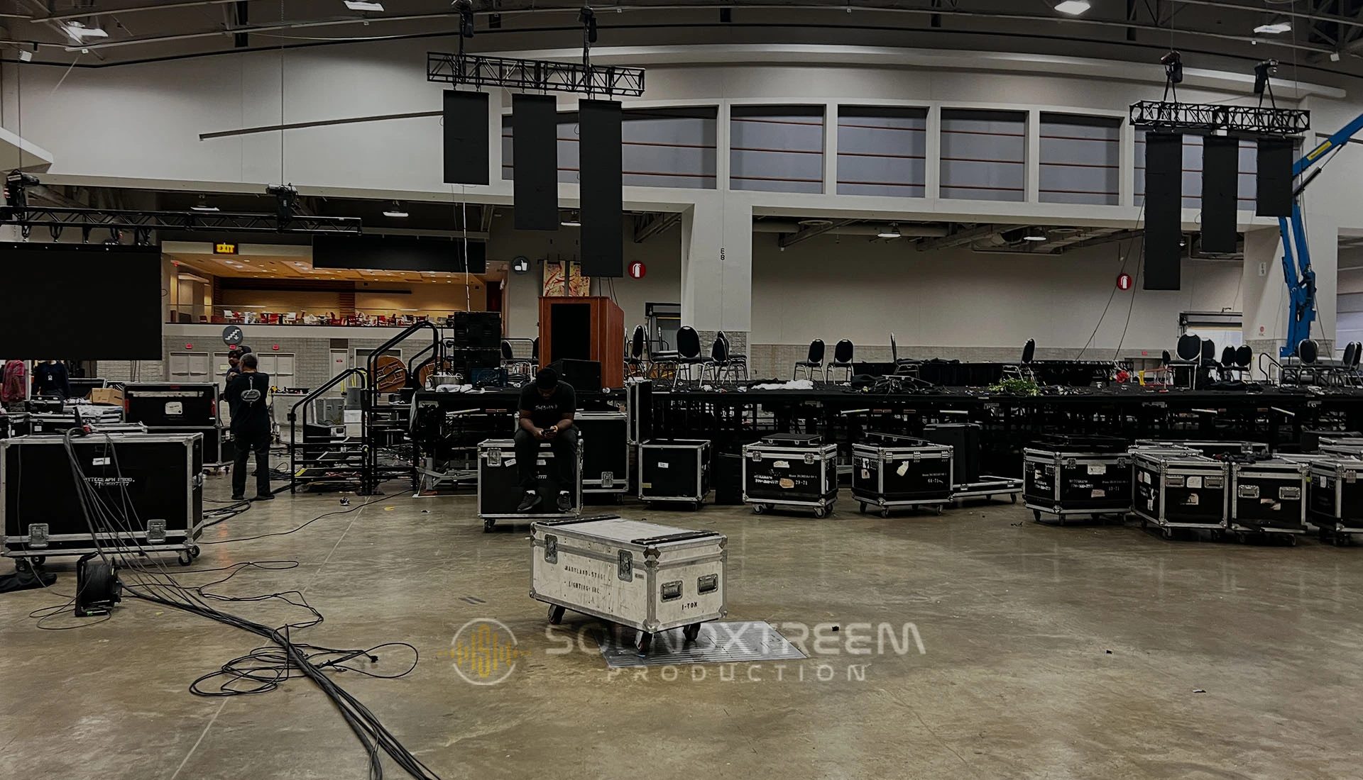 Soundxtreem crew loading in flown line-array speakers, trussing and road cases in a ballroom