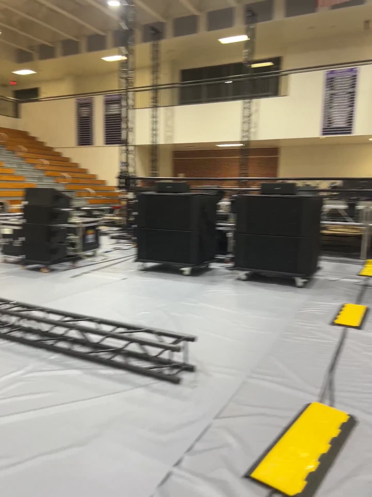 Stage monitors and truss sections staged on a gymnasium floor
