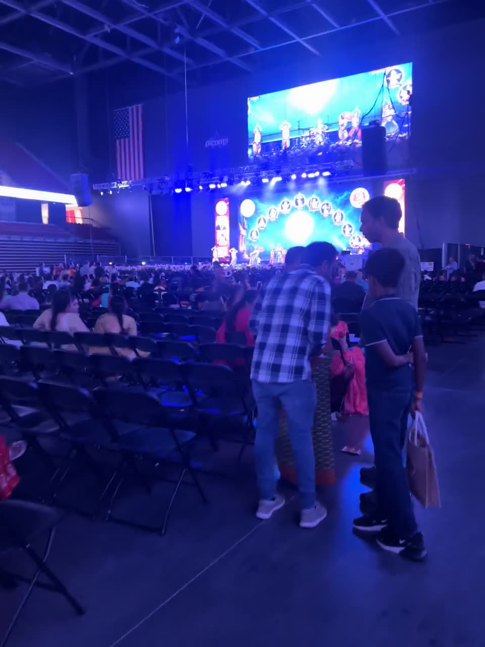 Crowd seated in an arena facing a brightly lit main stage