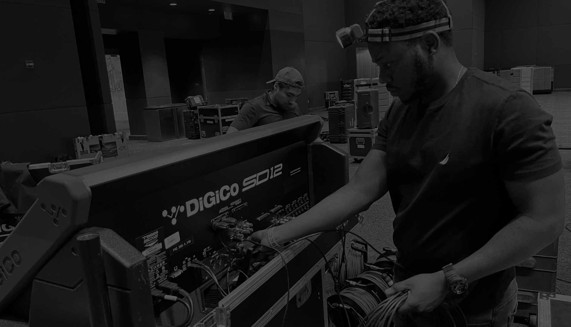 Soundxtreem crew members prepping a DiGiCo SD12 console and coiling cable during load-in